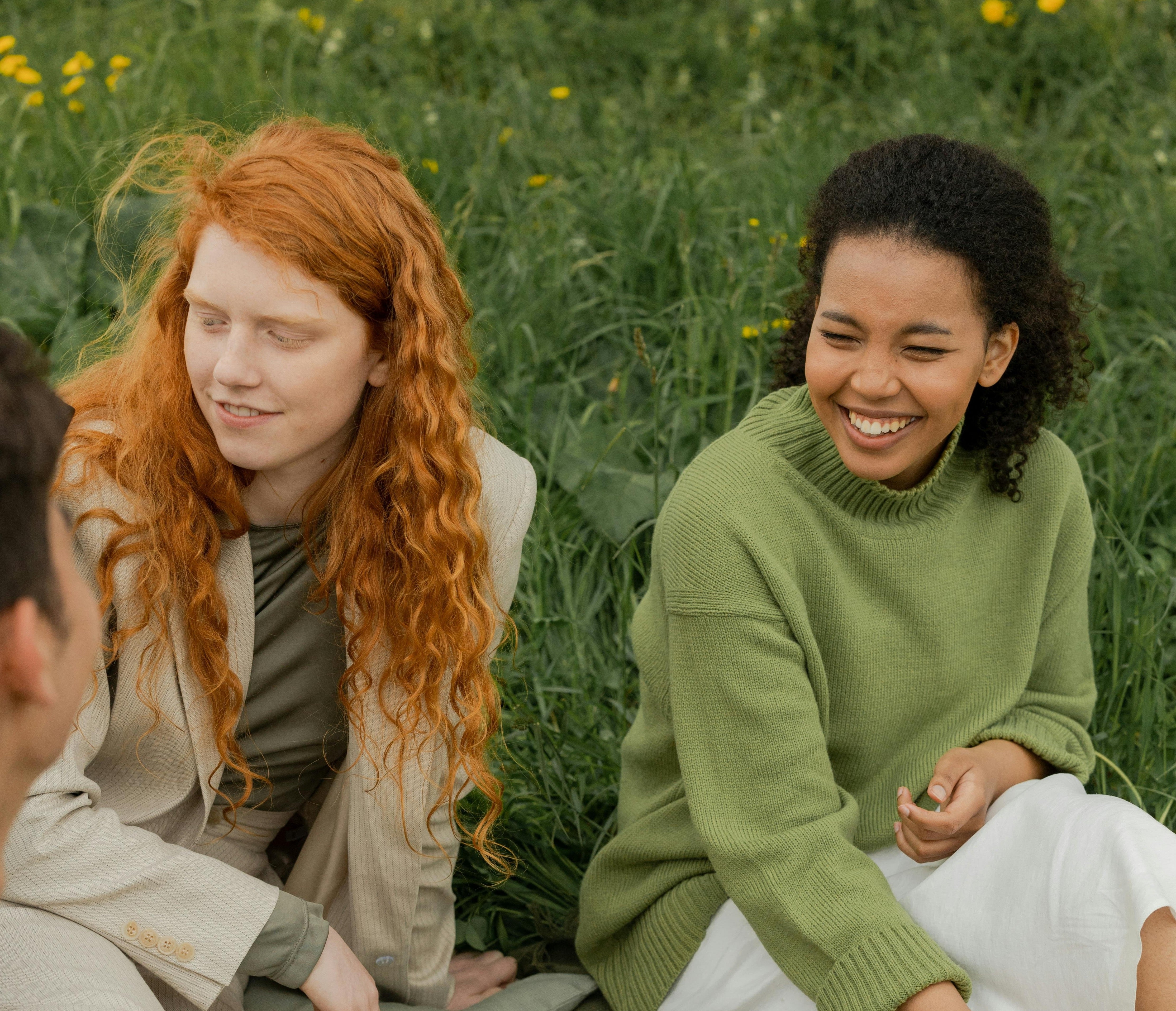 two people sitting on grass in a park